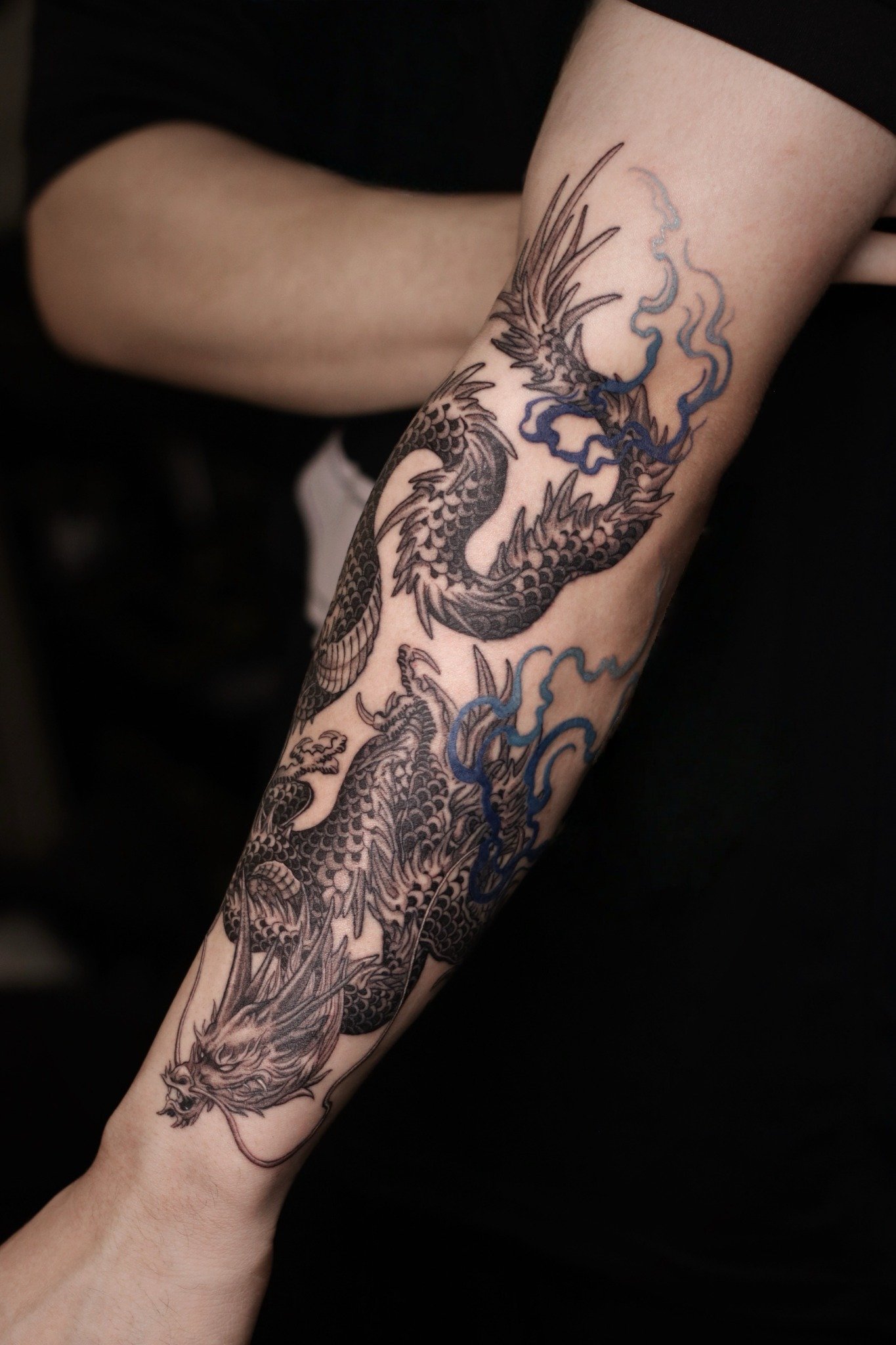 Twin dragon linework tattoo with blue accents by Hoang Bao at Overthink-Ink Saigon
